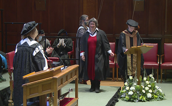 Sue walking onto stage during her graduation ceremony